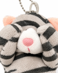 Close-up of a gray tabby cat plush charm with its paws covering its eyes, highlighting its soft fabric texture, white muzzle, pink inner ears, and pink nose.