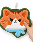 Hand touching the orange cat-face-shaped hand towel, showing its soft texture.