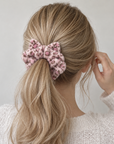 Woman wearing a soft, fluffy pink leopard-print cat ear scrunchie in a ponytail.