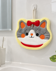 Cat face hanging hand towel displayed on a wall beside a bathroom sink.