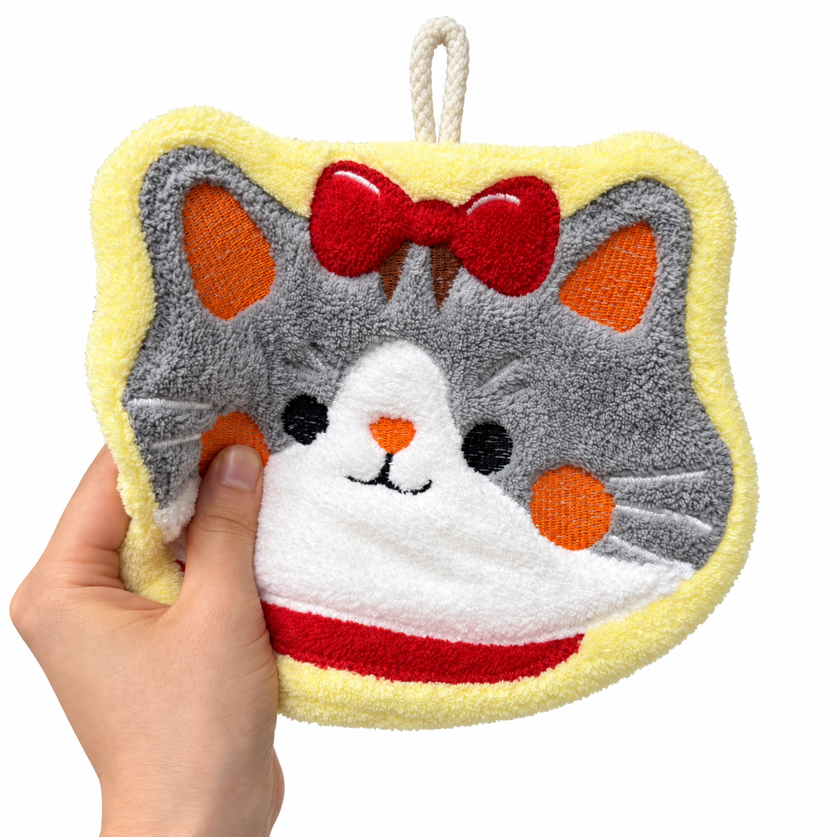 A hand gently pressing a cat face hanging hand towel to show its soft, plush texture.