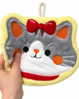 A hand gently pressing a cat face hanging hand towel to show its soft, plush texture.