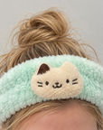 Mint green fluffy cat spa headband worn with hair tied up, featuring a cream cat appliqué.