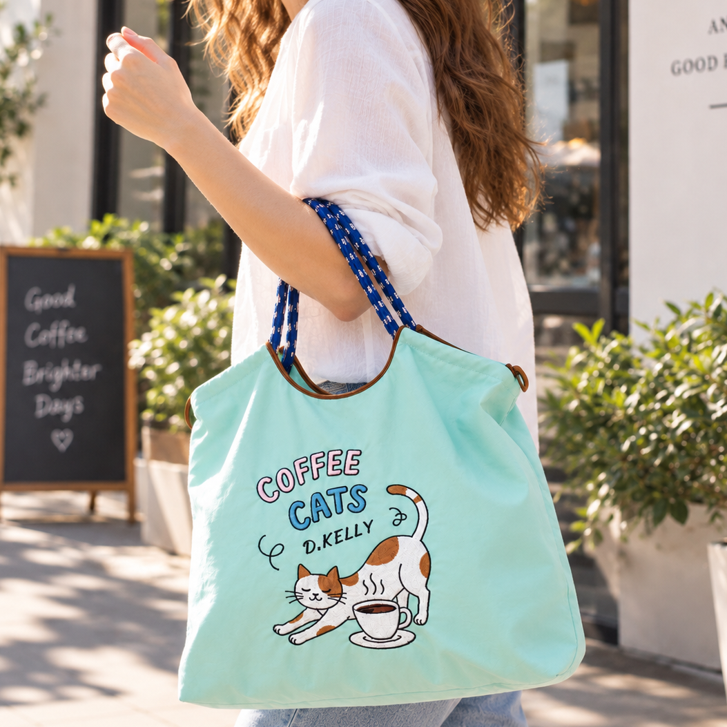 Woman in a white top carrying a mint green Coffee Cats tote bag on her arm while walking outdoors.
