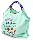 Angled view of a mint green Coffee Cats tote bag filled with items, featuring a stretching cat, coffee cup, and blue and white rope-style handles.