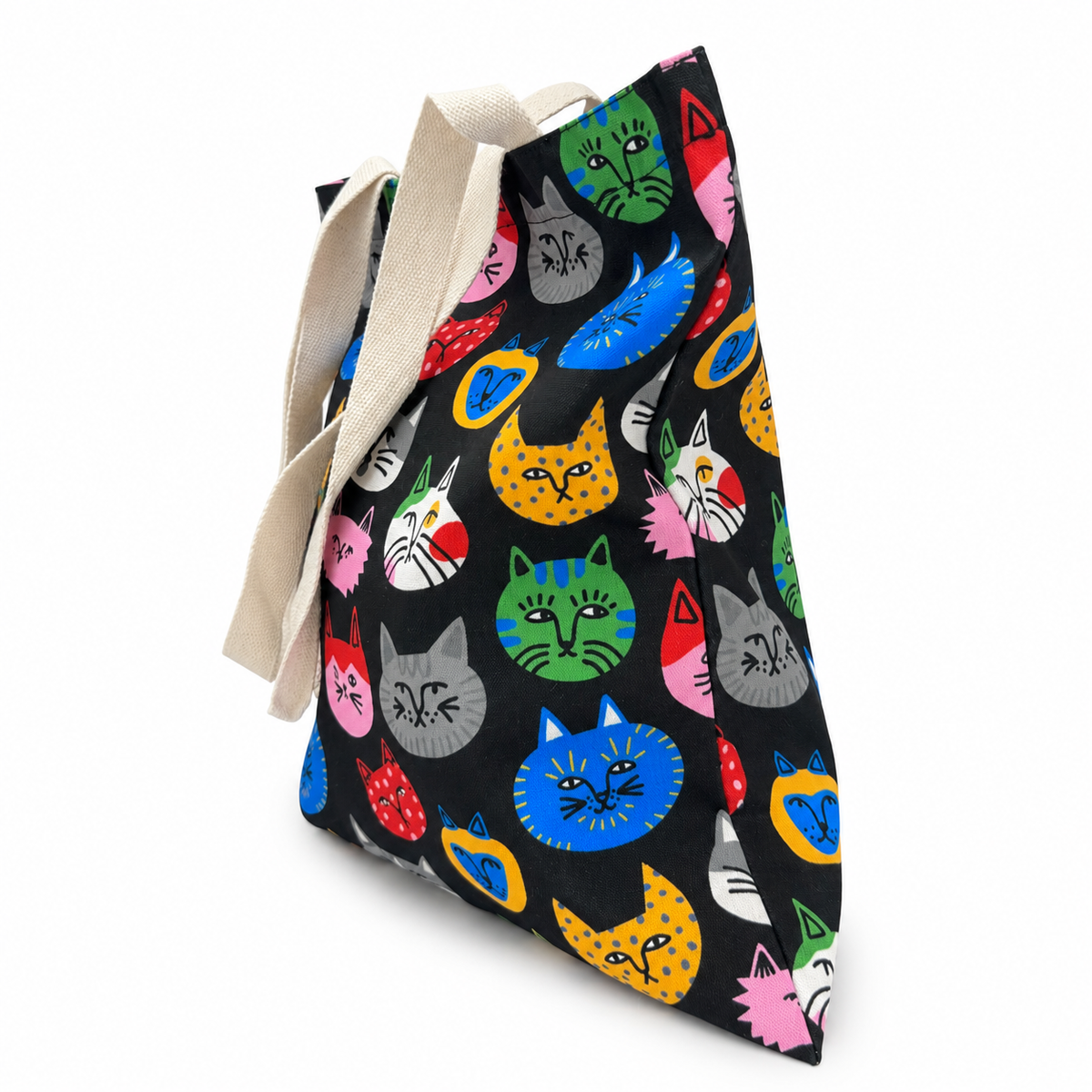 A colorful cat face tote bag filled with items, shown from the side to highlight its roomy shape and carrying capacity.