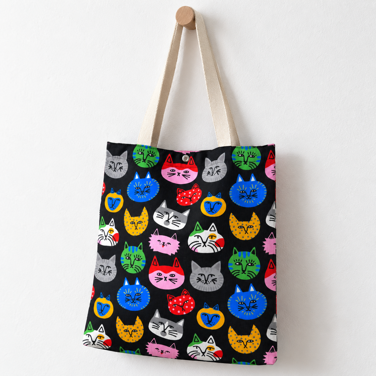 A colorful cat face tote bag hanging on the wall.