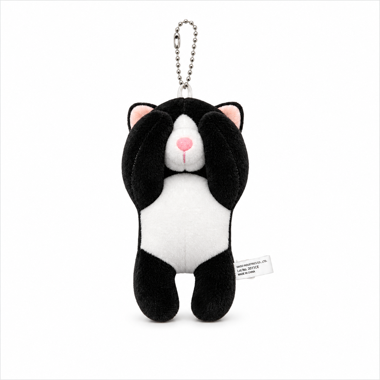 A tuxedo cat plush charm with its paws covering its eyes, a white muzzle, pink inner ears, and a pink nose, attached to a silver ball chain.