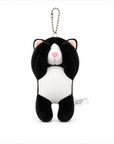 A tuxedo cat plush charm with its paws covering its eyes, a white muzzle, pink inner ears, and a pink nose, attached to a silver ball chain.