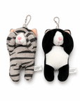 Two cat plush charms displayed side by side, one a gray tabby stripes and the other a tuxedo cat, both designed with their paws covering their eyes and attached to silver ball chains.