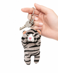 A gray tabby cat plush charm with its paws covering its eyes, attached to a key ring with keys, held in a person's hand.
