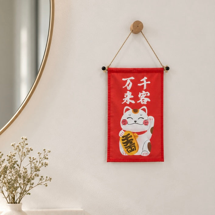 A Lucky Cat wall hanging displayed on a bright interior wall.