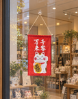 Red Lucky Cat wall hanging banner displayed on the glass window of a store.