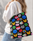 A woman is carrying a colorful cat face tote bag over her shoulder while walking outdoors.